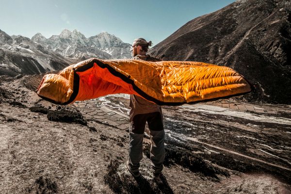 Randonneur présentant un sac de couchage de trekking dans un environnement de haute montagne