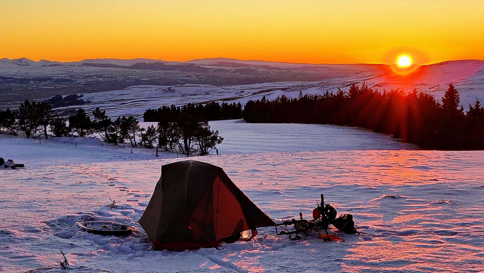 Bikepacking bivouac in the snow at sunset